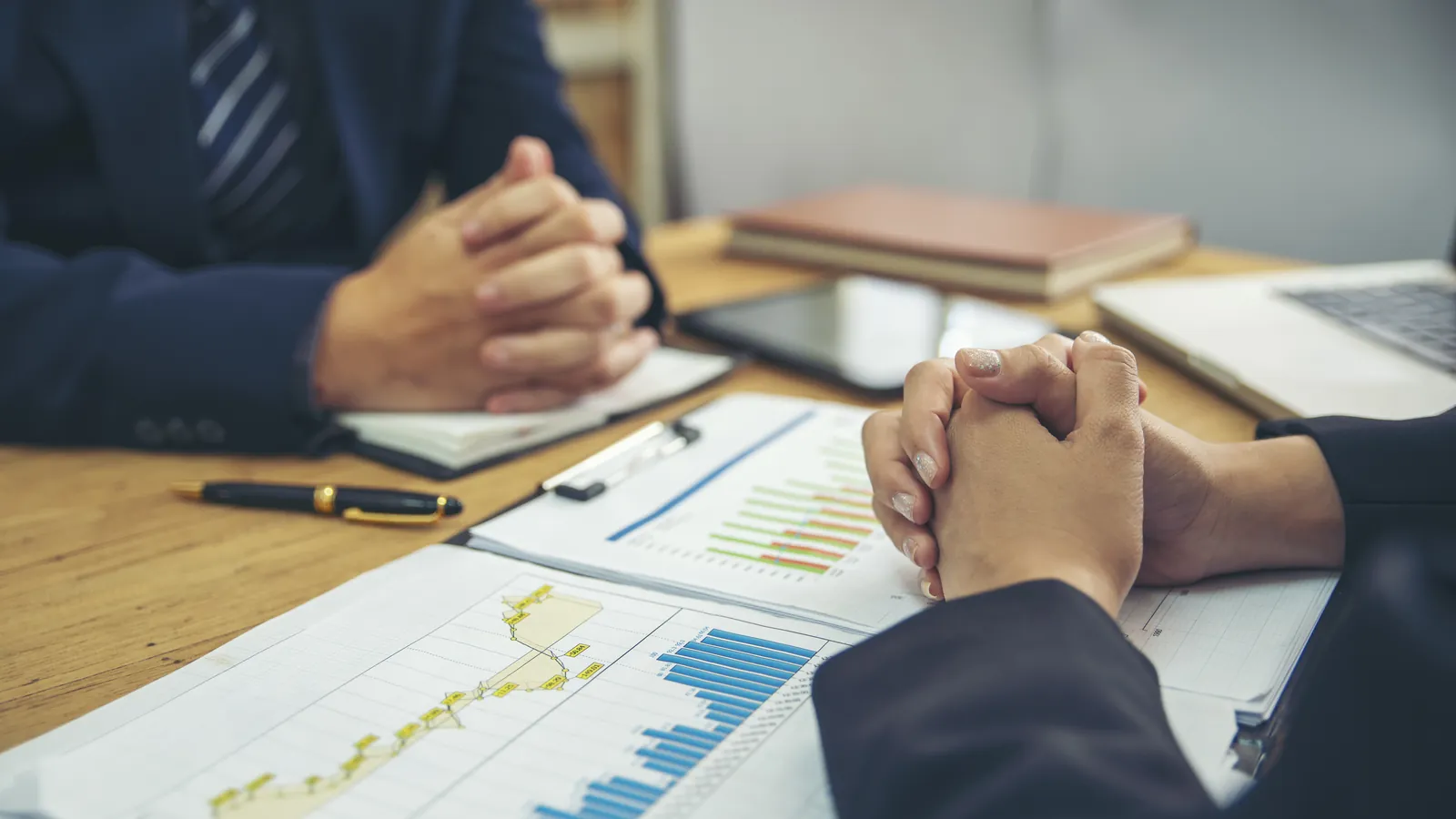 Finanzgespräch mit Diagrammen und Unterlagen auf dem Tisch