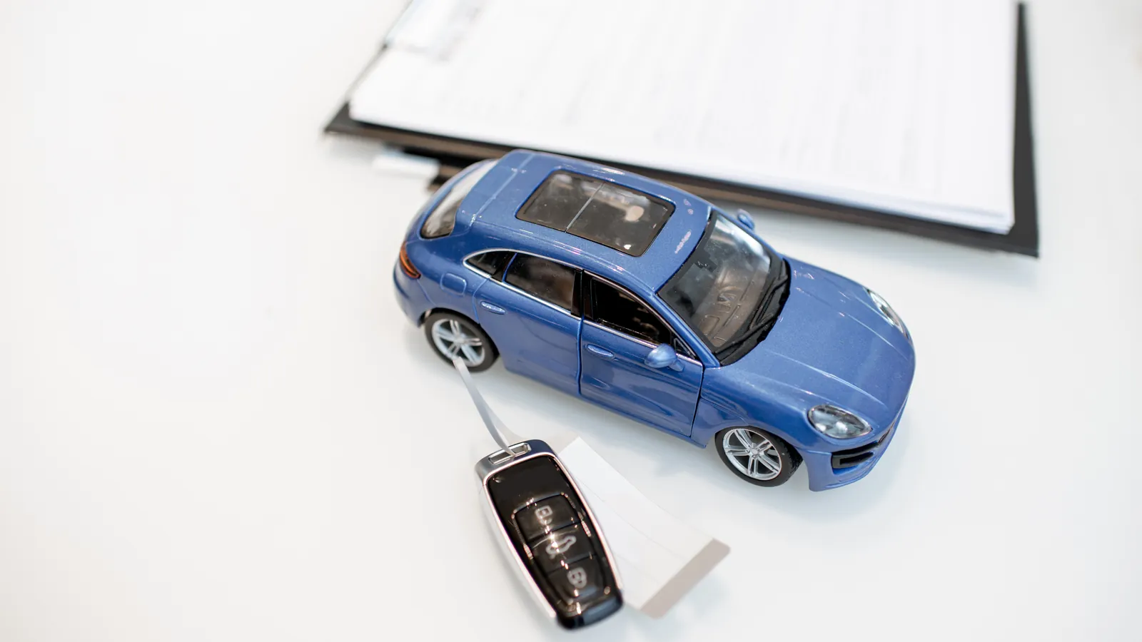 Autoschlüssel, Modellauto und Antragsunterlagen auf dem Tisch