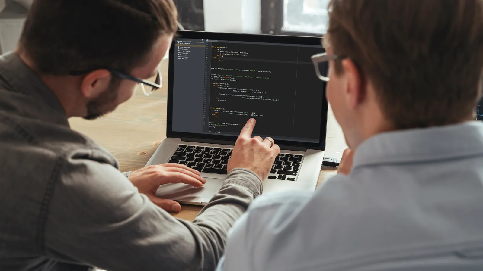 Zwei IT-Fachleute prüfen gemeinsam Code am Laptop