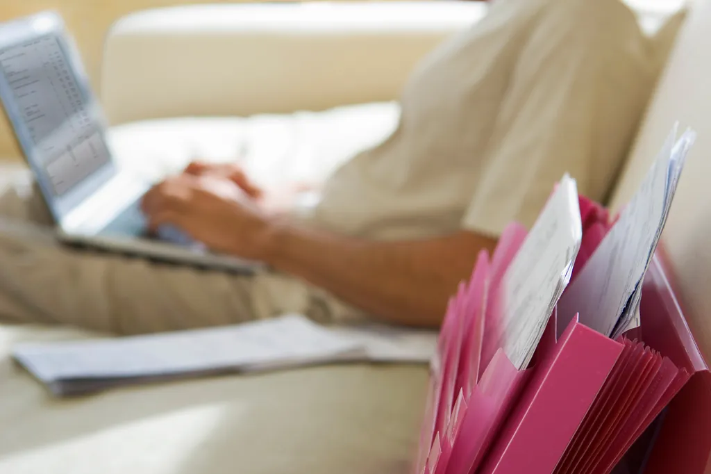 Selbstständiger ordnet am Laptop seine Unterlagen zur Rentenversicherung
