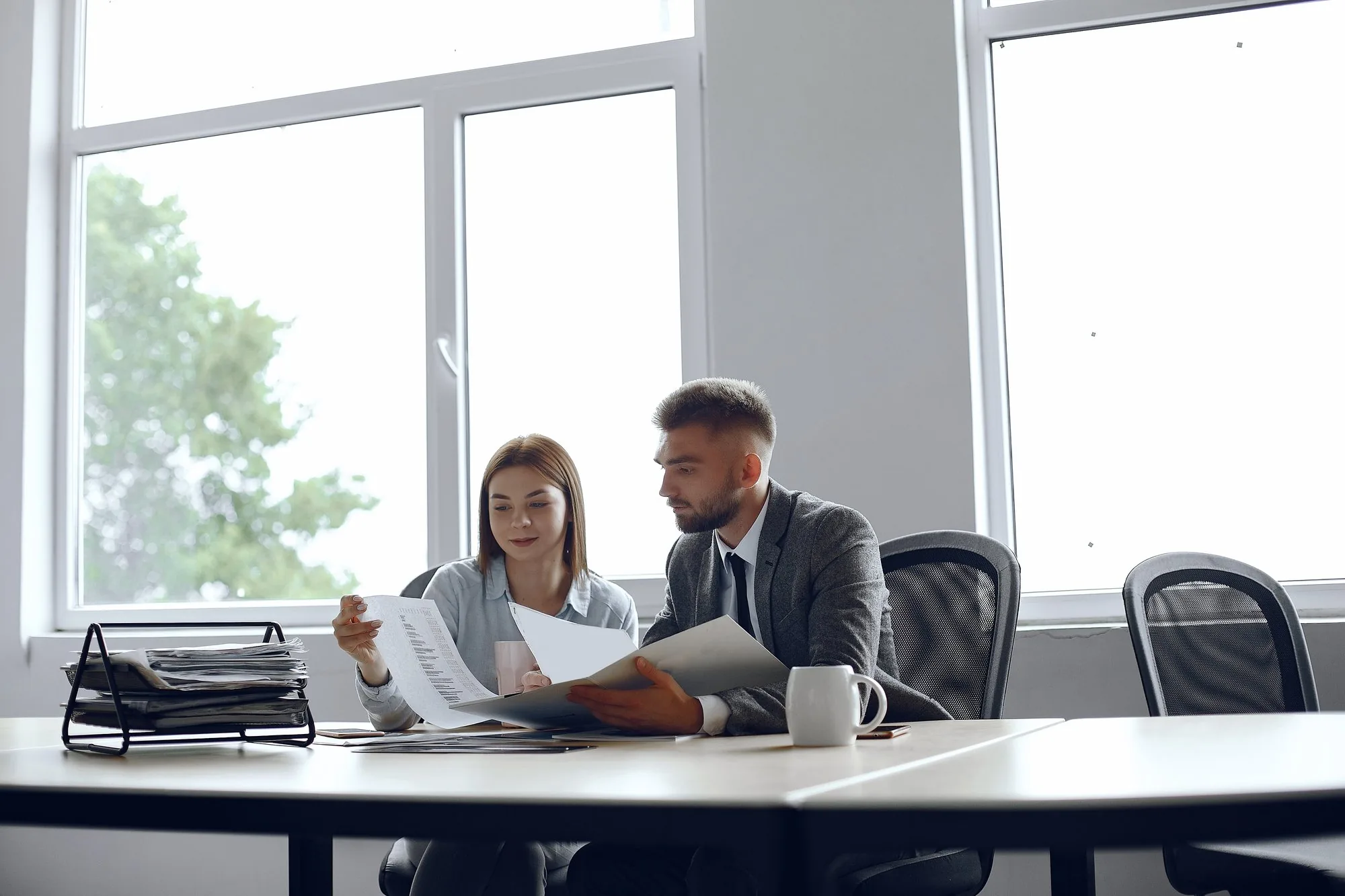 Zwei Kolleginnen und Kollegen prüfen gemeinsam Unterlagen im hellen Büro