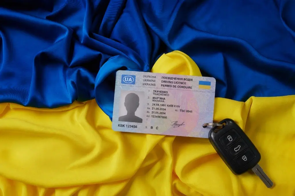 Ukrainischer Führerschein und Autoschlüssel auf einer blau-gelben Flagge
