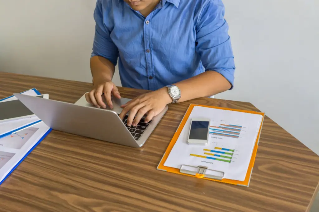 Selbstständige Person arbeitet konzentriert am Schreibtisch mit Unterlagen und Laptop